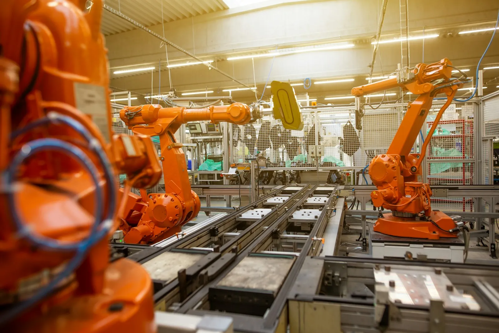 Bir üretim hattında çalışan turuncu robot kollar
